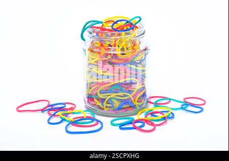 selection of colourful elastic bands in glass jar on white background Stock Photo