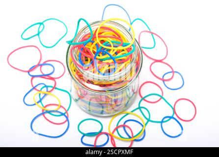 selection of colourful elastic bands in glass jar on white background Stock Photo