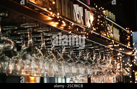 Clear bright wine glasses hanging in a bar. Reflecting ight and sparkling. Stock Photo