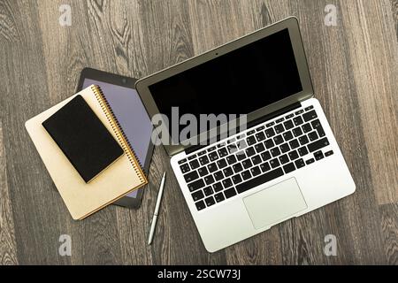 Workstation setup featuring a laptop, tablet, and notebooks on a wooden desk for productive study or office time Stock Photo