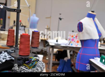 General view of a sewing workshop. Three spools of thread and a sewing mannequin in the foreground. Stock Photo