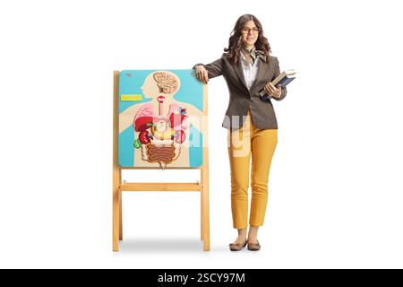 Full length portrait of a young female biology teacher leaning on a board with anatomical organ poster isolated on white background Stock Photo
