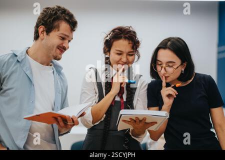 Three students collaborating on a school project in classroom Stock Photo