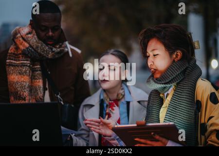 Multiracial team of people collaborating outdoors in casual winter clothing Stock Photo