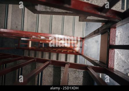 An old fence painted red on a staircase in a tall building. Stock Photo