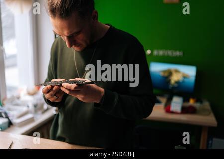 Portrait of focused technician carefully examining small component from laptop motherboard, troubleshooting and performing repairs in specialized Stock Photo