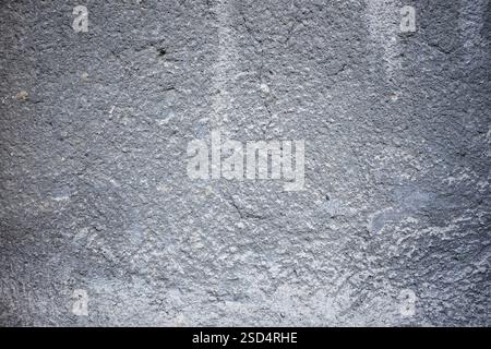 A gray concrete wall features a rough texture and subtle patterns. The surface shows slight imperfections, adding character to the structure. Natural Stock Photo