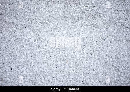 A close-up view of a textured concrete wall features a subtle gray tone with fine details. This surface offers a minimalist backdrop suitable for vari Stock Photo