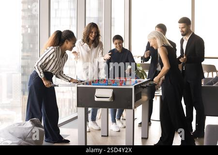 Group of happy multiethnic colleagues playing foosball Stock Photo
