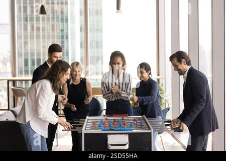 Group of multiracial colleagues gathered together for playing foosball game Stock Photo