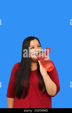 40-year-old Latina woman drinks water from environmentally friendly portable plastic bottle to take care of her health Stock Photo