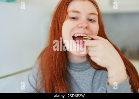 Girl with red hair eating trend Dubai chocolate with pistachio paste and kataifi dough.  Stock Photo