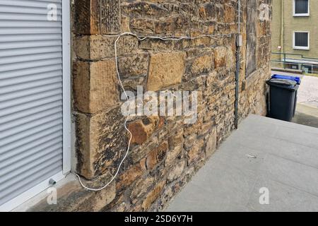 amateurishly laid telephone cable on a house wall, Germany Stock Photo