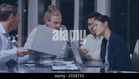 Collaborating on laptops, business team in office meeting late at night Stock Photo