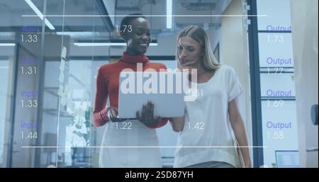 Two women collaborating in modern office, analyzing data on laptop screen Stock Photo
