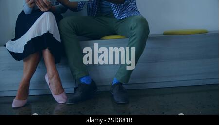 Couple sitting together on bench, holding hands and enjoying conversation indoors Stock Photo