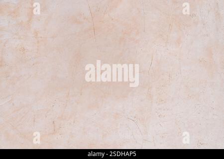 A textured beige plaster wall with subtle scratches and imperfections, creating a rustic and natural background surface. Stock Photo