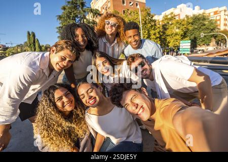 Frontal view of multi-ethnic group of happy friends taking selfie together in the street Stock Photo