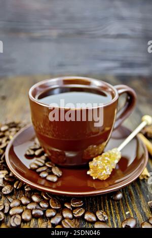 Coffee in cup brown with sugar, coffee beans and cinnamon sticks on a wooden boards background Stock Photo