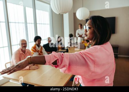 A confident Indian businesswoman leads an engaged team meeting. The atmosphere is collaborative and empowering, with team members actively listening. Stock Photo