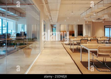 The image captures a modern coworking office with open seating and glass partitions. The spacious interior facilitates productivity and collaboration, Stock Photo