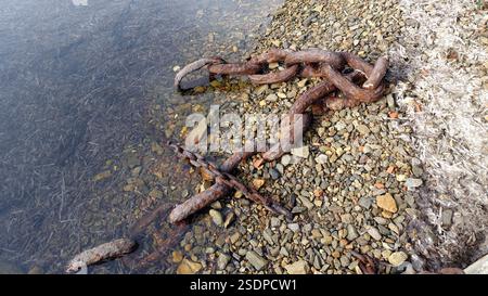 Rusty chains abandoned on a rocky beach. Stock Photo