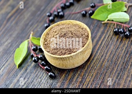Flour of bird-cherry in a bowl with black berries on a background of wooden boards Stock Photo