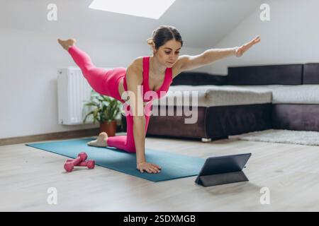 Woman instructing online yoga class stretching arms on a yoga mat. Concept of fitness, online teaching, and healthy lifestyle. High quality photo Stock Photo