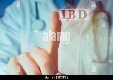 Cropped view of young male doctor in a white coat pointing finger up at the letters "IBD". Medical concept. Stock Photo