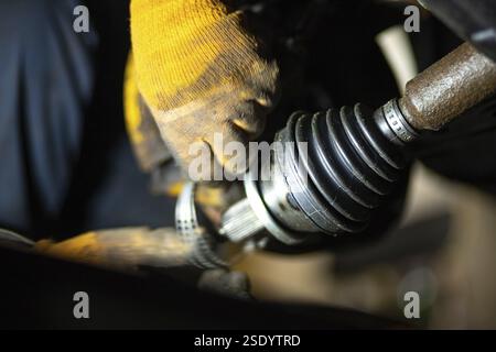Close-up of gloved hands adjusting a CV joint during vehicle maintenance Stock Photo