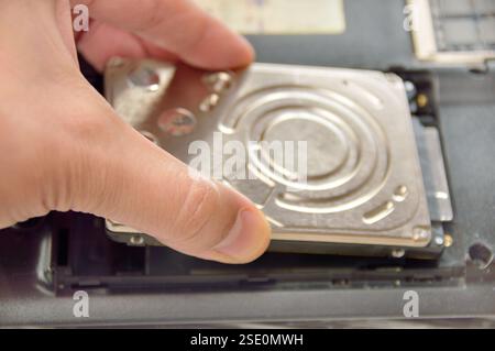 Works on service of computers in the service center.  Installing of the hard drive from the notebook Stock Photo