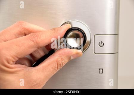 Conceptual image of the hand of a man checking the health of his computer using a stethoscope as he checks for malware and viruses or any electronic m Stock Photo