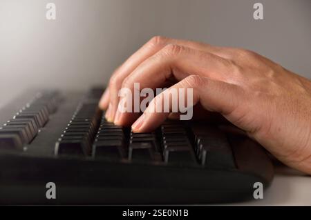 close up of a male hand using a computer keyboard thumb.Playing computer games at night Stock Photo