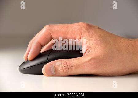 close up of a male hand using a computer mouse thumb.Playing computer games at night Stock Photo