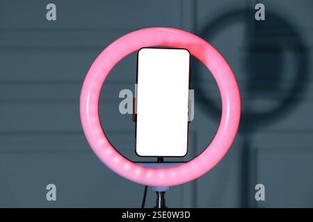 Ring lamp with smartphone against wall indoors Stock Photo