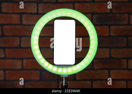 Ring lamp with smartphone against brick wall Stock Photo