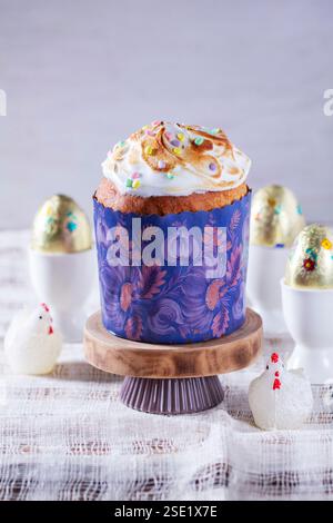 Easter cake, chocolate eggs in gold foil and chicken-shaped candles on a light background. Stock Photo