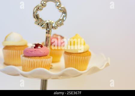 Strawberry and lemon cupcakes on a traditional cake stand for Easter and afternoon tea; concept for teatime, Birthdays and Mother's Day. Stock Photo