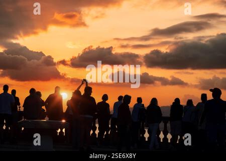 Nice, France -November 04,  2024 - Silhouettes of people enjoying a breathtaking sunset on a scenic viewpoint overlooking the sea and the promenade of Stock Photo