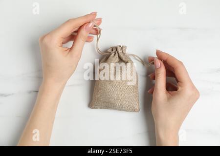 Woman with burlap bag at white marble table, top view Stock Photo
