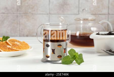 Glass of tea in metal holder served on white wooden table Stock Photo
