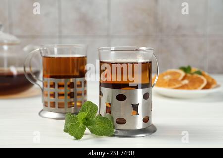 Glasses of tea in metal holders served on white wooden table, closeup Stock Photo