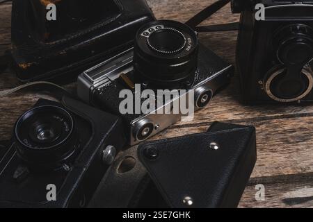 Old vintage cameras and leather cases on wooden background. Closeup Stock Photo