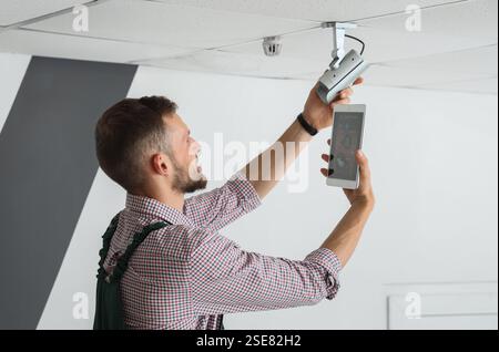 Male worker with tablet computer installing alarm system in room Stock Photo