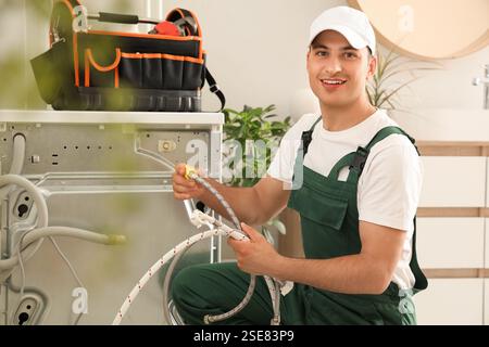 Male plumber fixing washing machine in bathroom Stock Photo