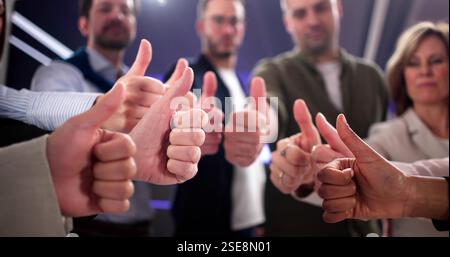 Smiling business team gives thumbs up for successful deal. Stock Photo