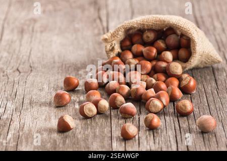 Hazelnuts, filbert in burlap sack on rustic wooden table. heap or stack of hazel nuts. Hazelnut background, healty food Stock Photo