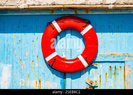 Red color lifebelt on old wooden door of fishing house, Klima village, Milos island, Cyclades, Greece Stock Photo