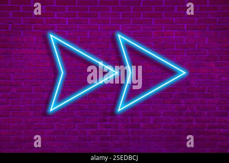 Bright neon arrow-shaped pointer on brick wall Stock Photo