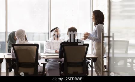 Multinational businesspeople listening speech of young Brazilian female team leader Stock Photo